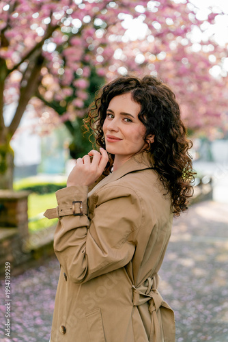 Closeup Portrait of young woman near blooming pink sakura. Spring. Unity with nature.