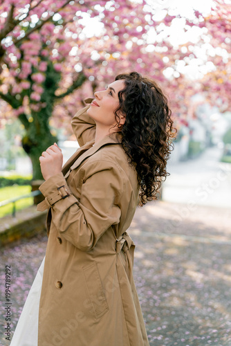Young woman resting near blooming pink sakura. Spring. Unity with nature.