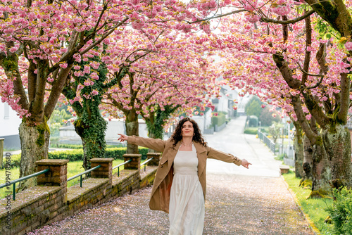 Young woman resting near blooming pink sakura. Spring. Unity with nature.