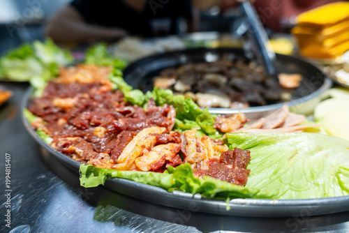 Korean BBQ Feast with Marinated Meat, Fresh Lettuce Wraps, and Hot Pot at a Restaurant Table