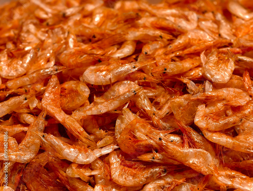 Close-up of a heap of orange-red dried shrimps, showing dry texture and rich details