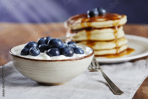 Pancakes With Blueberries and Yogurt on Table With Syrup and Juice in Morning...