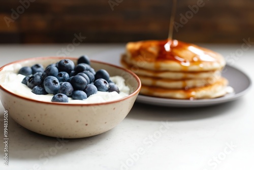 Blueberries on Yogurt With Pancakes and Flowers in the Kitchen Setting During...