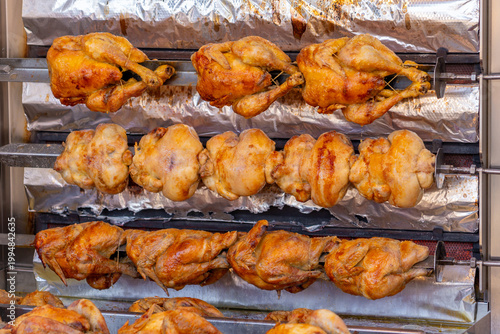 A market stall features an industrial grill oven that cooks whole chickens
