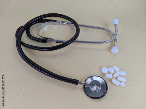 stethoscope on a white background. Stethoscope with white tablets symbolizing healthcare, medical diagnosis and treatment on a neutral background.
