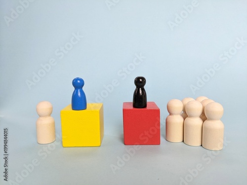 business team concept. Wooden figurines on colored cubes against blue background, symbolizing leadership, hierarchy, teamwork and social organization. Business and leadership concept