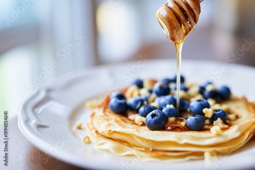 Delicious Pancakes Topped With Blueberries and Honey on a White Plate in Brig...
