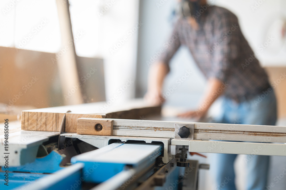 Fototapeta premium Carpenter cutting wood with a table saw in workshop