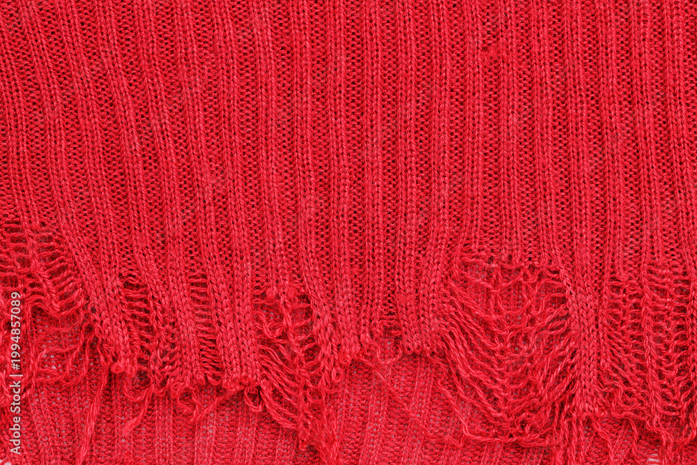 Obraz premium Texture of red knit fabric with loose threads and frayed edges showing design and structure in close-up view