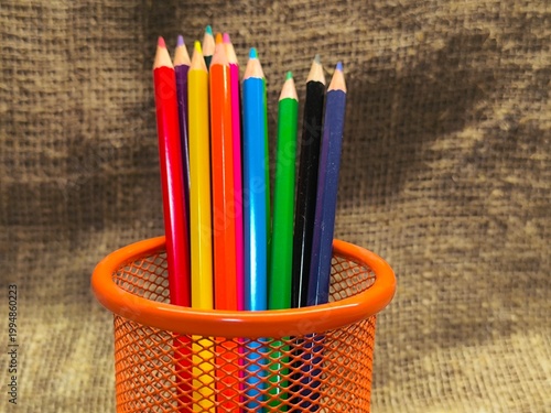 Multicolored pencils in a stand on the table, office desk.