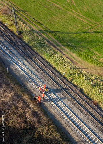 Aerial view of railway track with workers and adjacent green field scenery