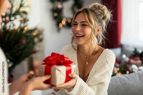 Woman Smiles While Receiving a Gift During a Holiday Gathering With Decoratio...