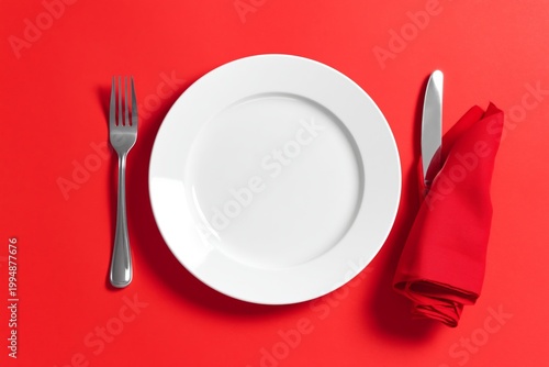 Table Setting With Cutlery and a Blank Plate on a Red Background