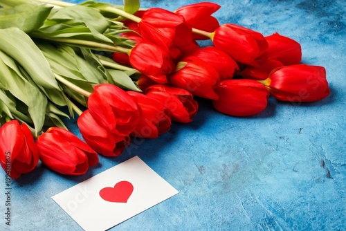Bouquet of Red Tulips With a Card on a Blue Table Surface in a Warm Setting