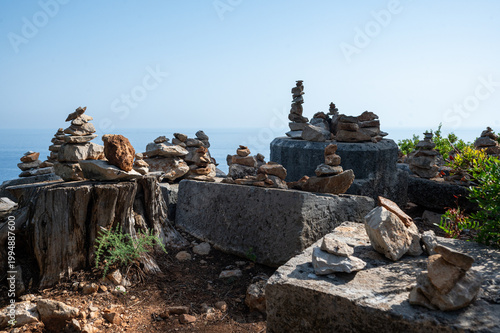 multiple balanced stone cairns arranged on weathered wooden stumps and rough stone blocks. Concept of harmony, mindfulness, and natural balance.
