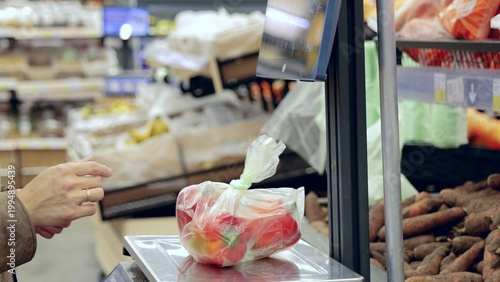 Photos Shopper using a digital scale to weigh fresh bell peppers in a supermarket, sele