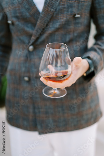 Man drinks cognac. Relaxed gentleman in tailored attire sipping Cognac during elegant afterhours gathering