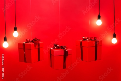 Bright Red Gifts Hanging With Lights Against a Red Background During a Festiv...