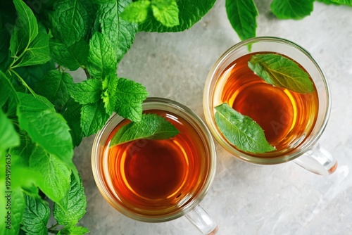 Freshly Brewed Tea With Herbs in Clear Cups on a Wooden Table Surrounded by G...