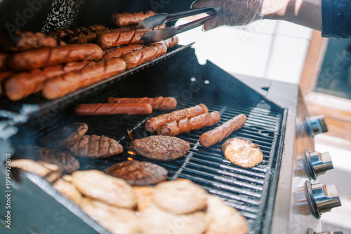 Barbecue feast scene. Cooking on charcoal grill. Juicy grilled sausages and burgers at summer gathering