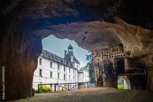 Detailed view of Brantome Abbey framed by ancient Troglodyte Cave opening, France.