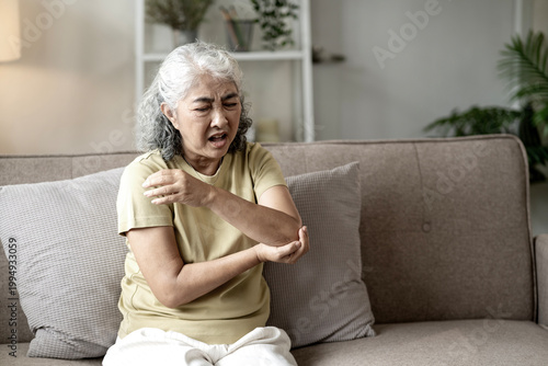 Cuadro en lienzo Senior Asian Woman Suffering from Elbow Joint Pain While Sitting on Sofa at Home