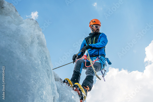 Obraz na plátně Climber in vibrant colors belaying down serac on icy glacier during Lenin peak ascent under clear sky with snow-covered peaks in background