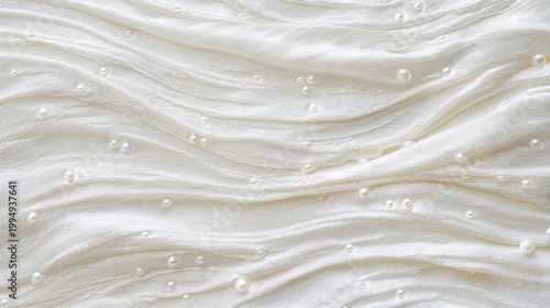 A soft, white fabric draped elegantly with small pearls scattered across its surface, showcasing a gentle texture and serene aesthetic.