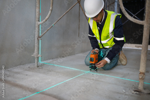 Construction worker using laser level on concrete floor building site action photography urban setting close-up precision measurement