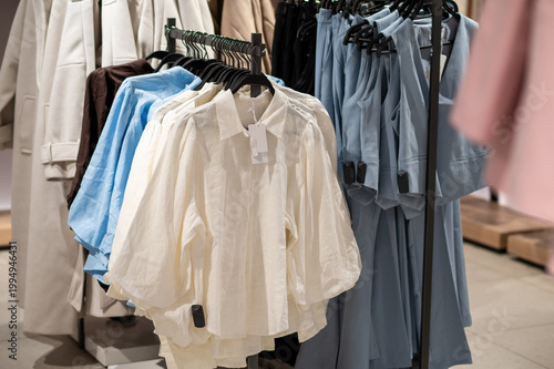 White and Blue Women's Blouses with Puff Sleeves on Hangers in Fashion Retail Store Display