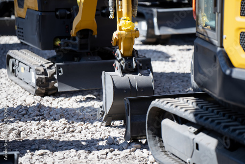 Фотография Multiple compact excavators on gravel with trench buckets, blades and rubber tra