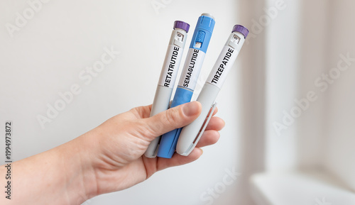 Hand holding semaglutide tirzepatide and retatrutide injection pens, GLP-1 weight loss and diabetes treatment
