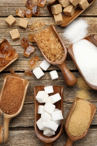 Cuadro en lienzo Different types of sugar in scoops on wooden table, flat lay