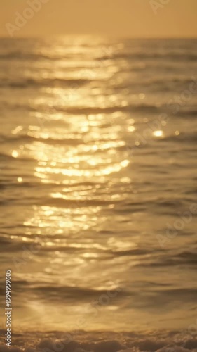 Golden sunset ocean sea wave water reflection bokeh background, warm shimmering seascape with gentle waves and soft glowing bokeh highlights view