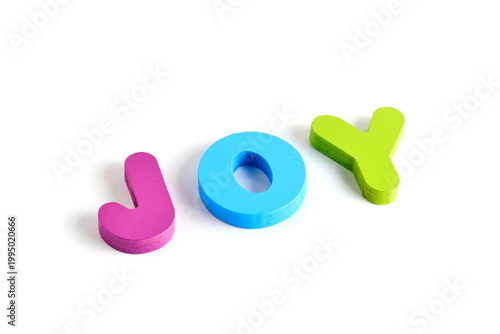 Side angle shot word JOY in foam letters, showing depth and soft shadows on white background.