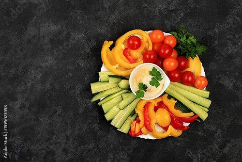 Middle East plate, Healthy food cuisine background with hummus bowl and raw vegetable sticks, nuts and dried apricots. Hummus platter with appetizers,traditional vegan snacks,oriental cuisine concept