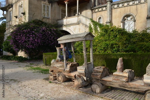 Blooming bougainvillea and vegetation in the park in front of the Busaco Palace in Portugal Coimbra region. Themes include travel, cultural heritage, and natural beauty.