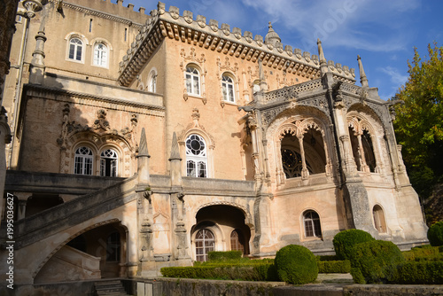 Blooming bougainvillea and vegetation in the park in front of the Busaco Palace in Portugal Coimbra region. Themes include travel, cultural heritage, and natural beauty.