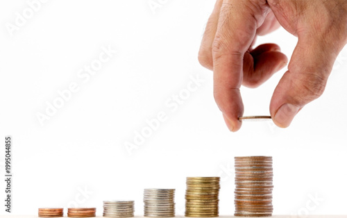 Hand stacking coins in ascending order symbolizing savings investment and financial growth on white background