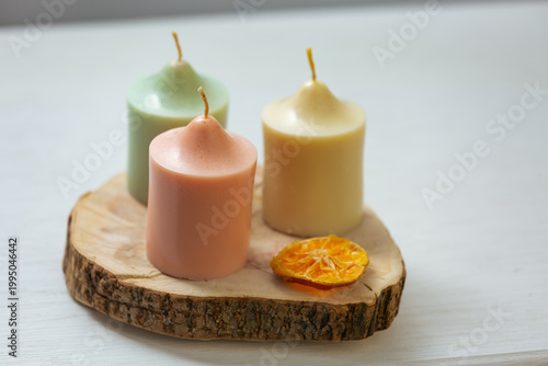 A collection of three colored harmony not burning design wax candles with dried natural orange in pastel colors in home interior. Closeup bath, care, spa, wellness, relaxation. In different angles