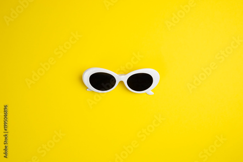 white sunglasses on yellow background. Copy space.