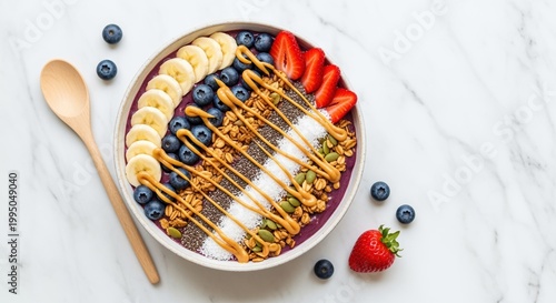 colorful acai bowl with mixed fruits and granola on marble background with wooden spoon