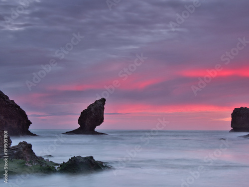 Vibrant Twilight Sky over Coastal Sea Stacks - Spectacular long exposure capturing a striking purple and magenta sunset over the ocean, with milky water surrounding dark sea stacks in Asturias, Spain.
