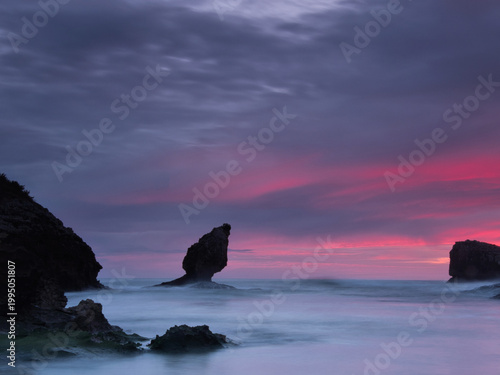Vibrant Twilight Sky over Coastal Sea Stacks - Spectacular long exposure capturing a striking purple and magenta sunset over the ocean, with milky water surrounding dark sea stacks in Asturias, Spain.
