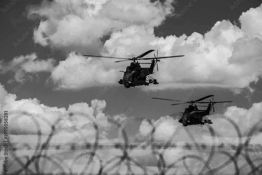 Naklejka premium Military helicopters patrolling sky over razor wire fence