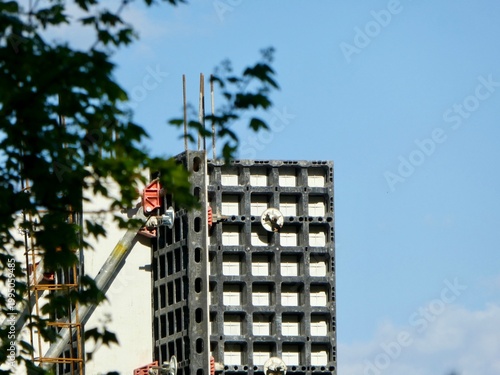 Industrial structures framed by green leaves under bright daylight