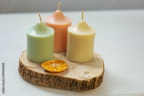A collection of three colored harmony not burning design wax candles with dried natural orange in pastel colors in home interior. Closeup bath, care, spa, wellness, relaxation. In different angles