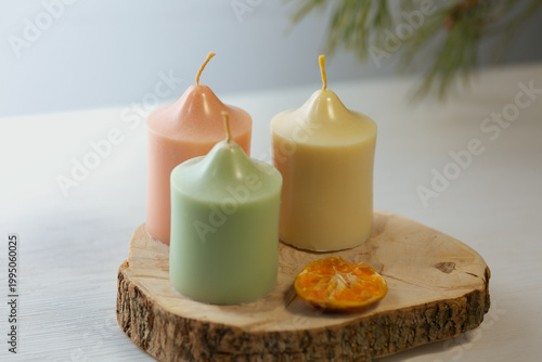 A collection of three colored harmony not burning design wax candles with dried natural orange in pastel colors in home interior. Closeup bath, care, spa, wellness, relaxation. In different angles