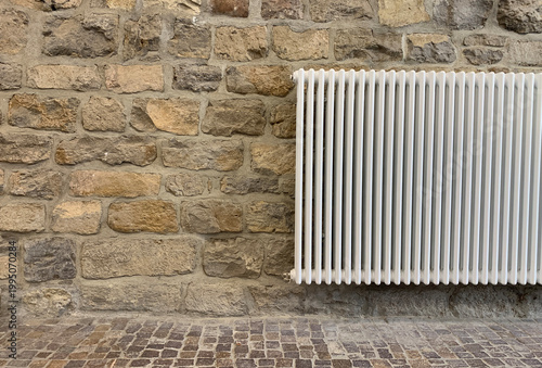 Cobblestone pavement and stone wall with heating radiator. Traditional European texture, rustic outdoor