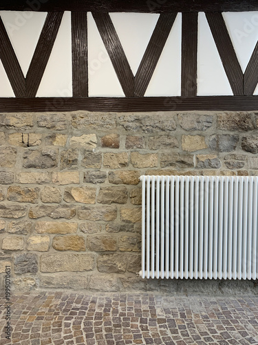 Radiator on textured wall with wooden elements. Cozy interior and home heating system